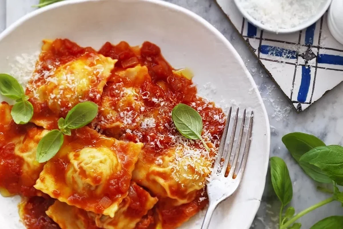 Bowl of cooked ravioli with sauce on a kitchen table