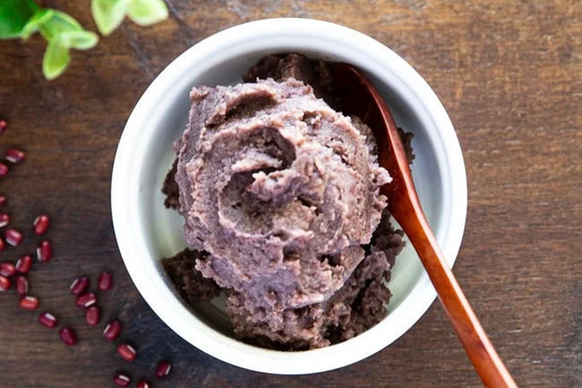 Bowl of smooth red bean paste with buns and dessert ingredients on a kitchen counter