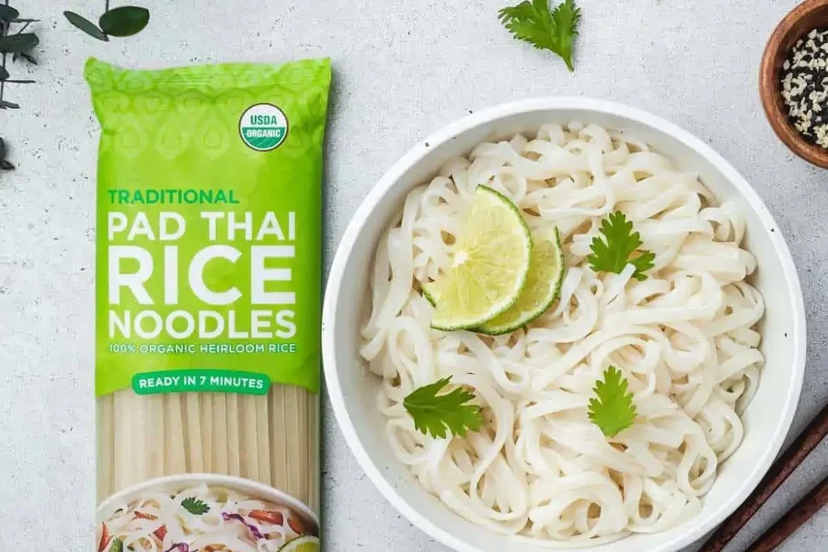 Bowl of rice noodles and pasta ingredients with vegetables and sauce in a home kitchen