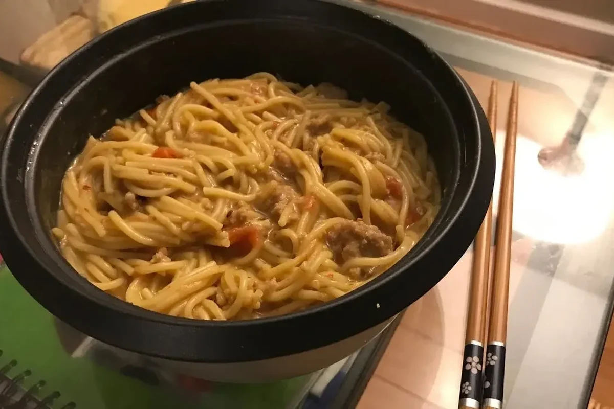 Bowl of rice pasta with vegetables and sauce in a bright home kitchen