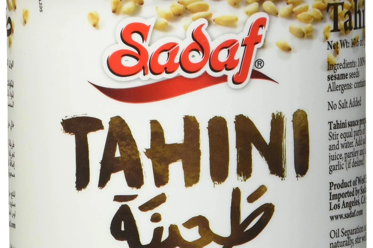 Jar of tahini and darker sesame paste side by side on a kitchen counter