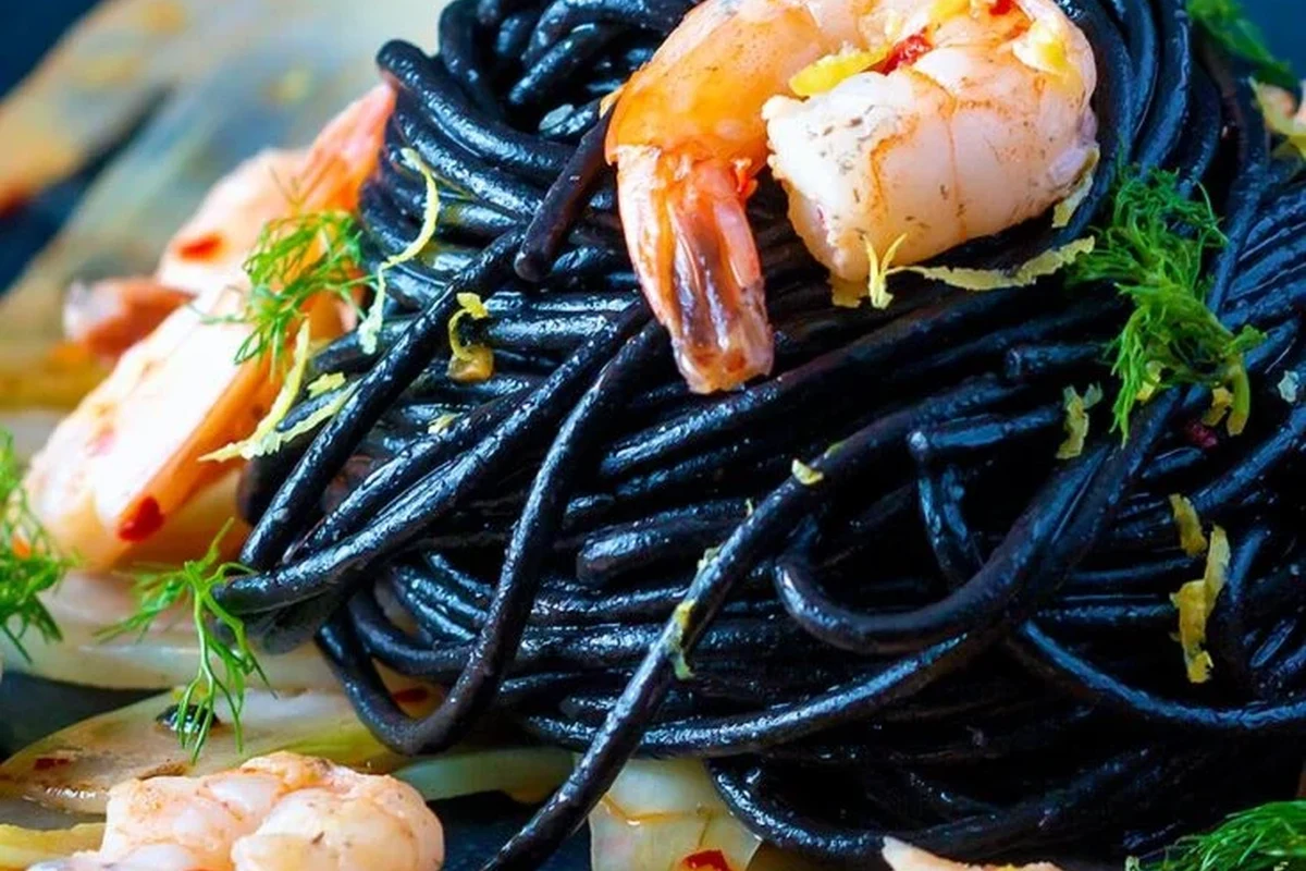 Black squid ink pasta served with seafood and herbs in a bright home kitchen