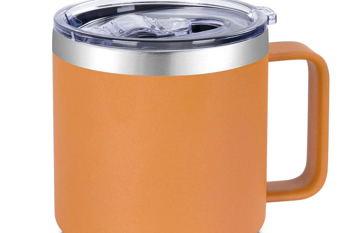 Stainless steel coffee mug with lid beside a coffee maker on a kitchen counter