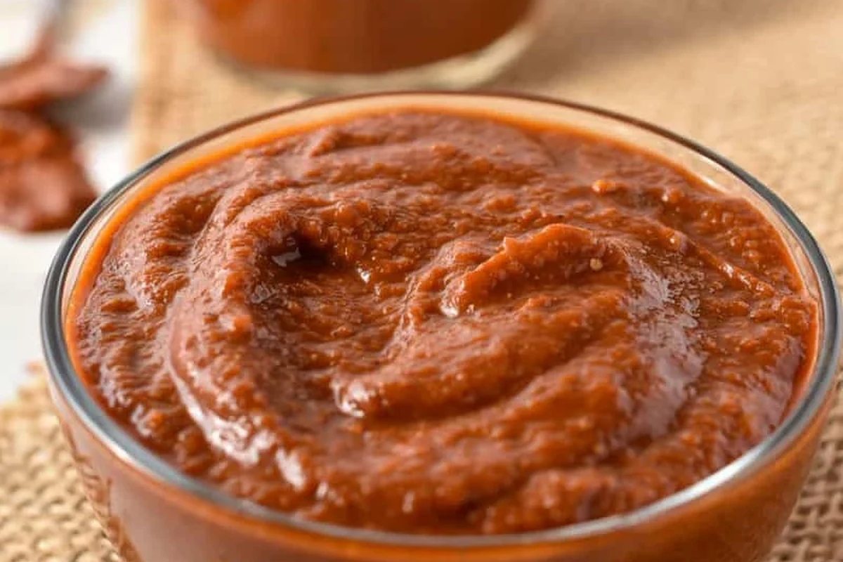 Jar of Tex-Mex paste beside pasta, spices, and a spoon on a kitchen counter
