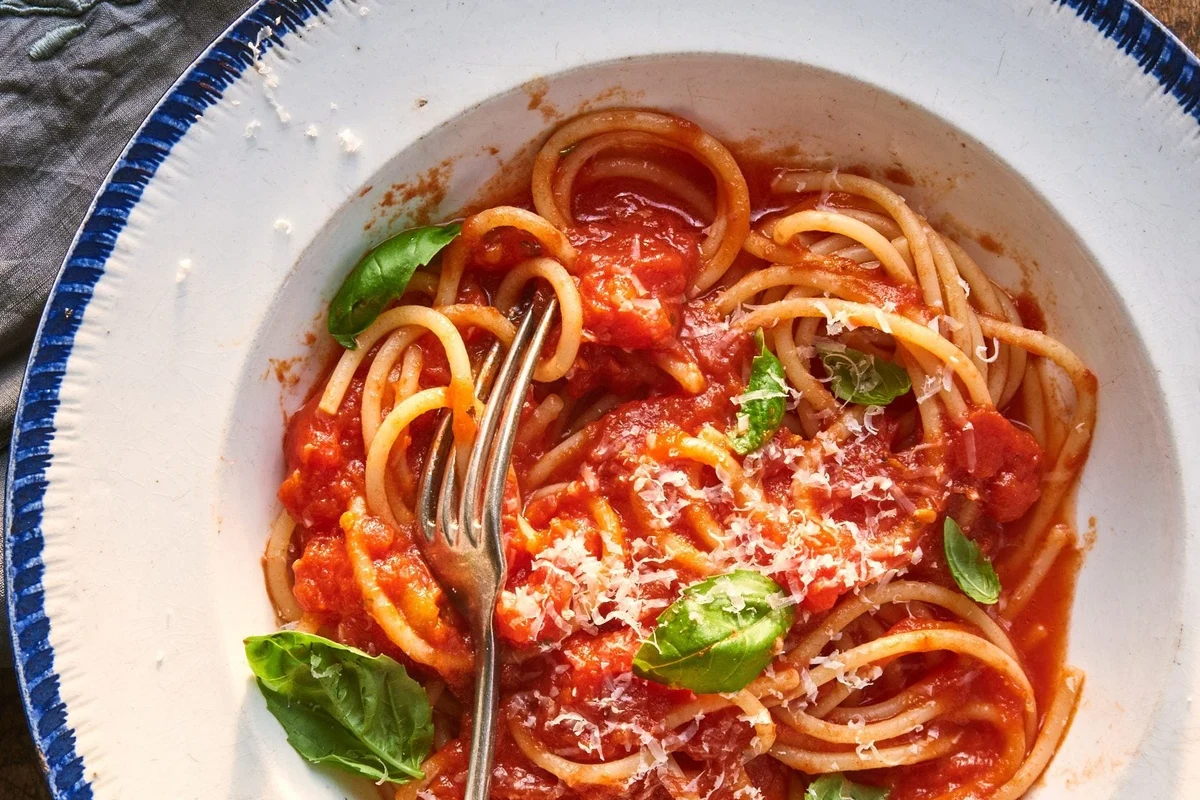 Jar of tomato sauce and bowl of pasta sauce beside cooked spaghetti in a home kitchen