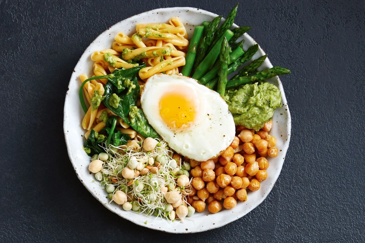 Bowls of whole wheat, legume, and gluten-free pasta with vegetables on a kitchen table