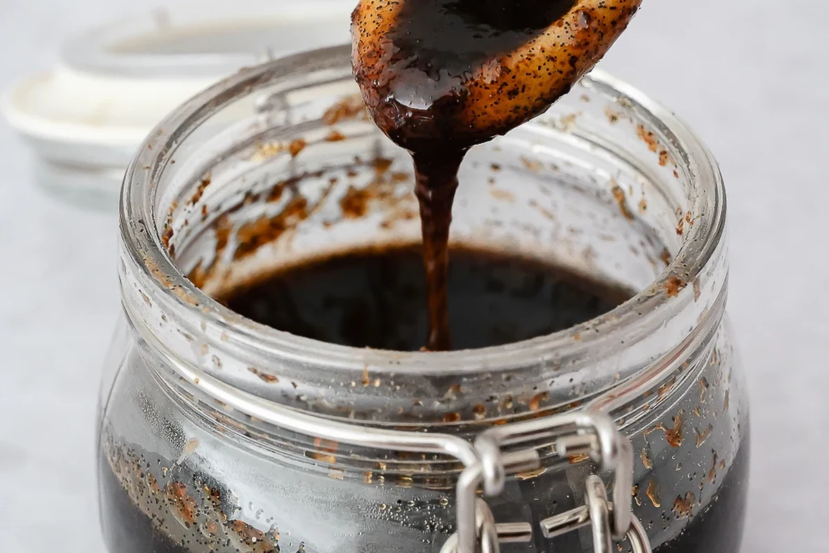 Jar of vanilla bean paste with vanilla specks beside a mixing bowl in a bright kitchen