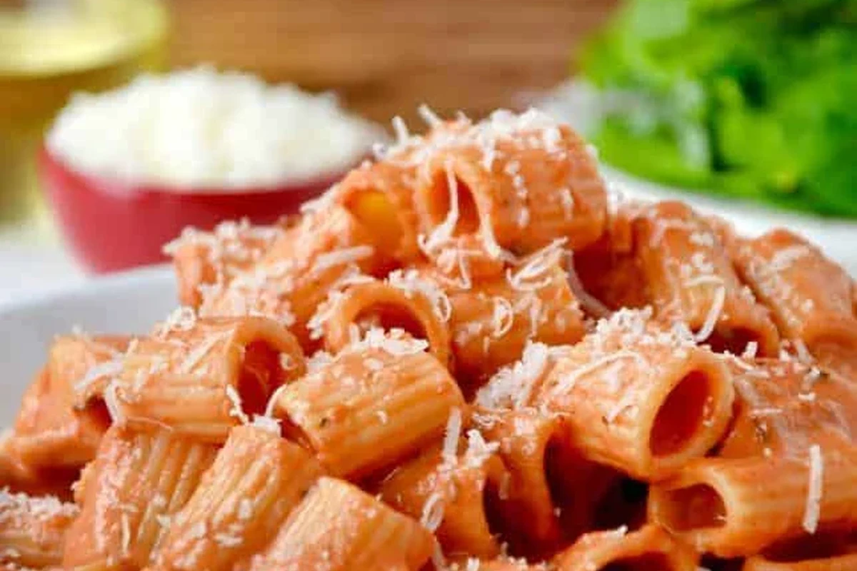 Creamy vodka pasta with tomatoes, basil, and a light garnish in a home kitchen bowl