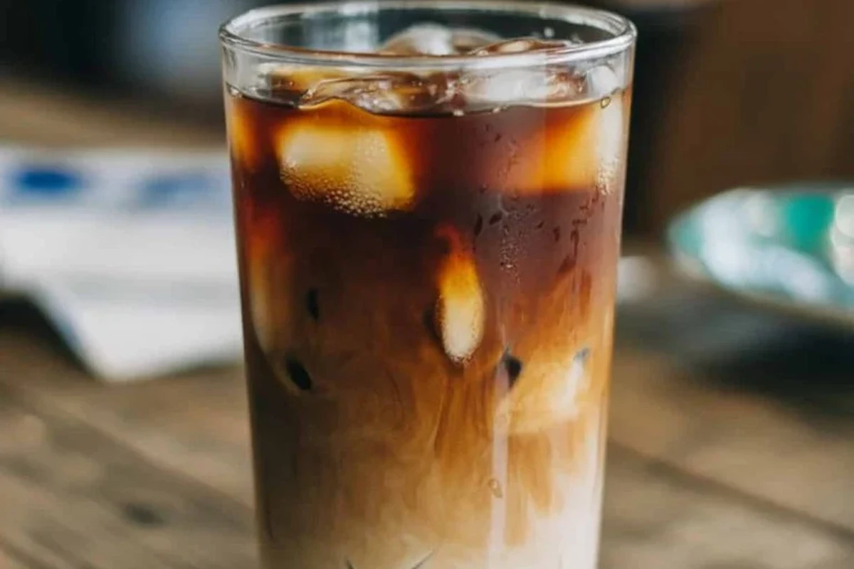Glass of cold brew coffee on a kitchen counter with ice and a small spoon