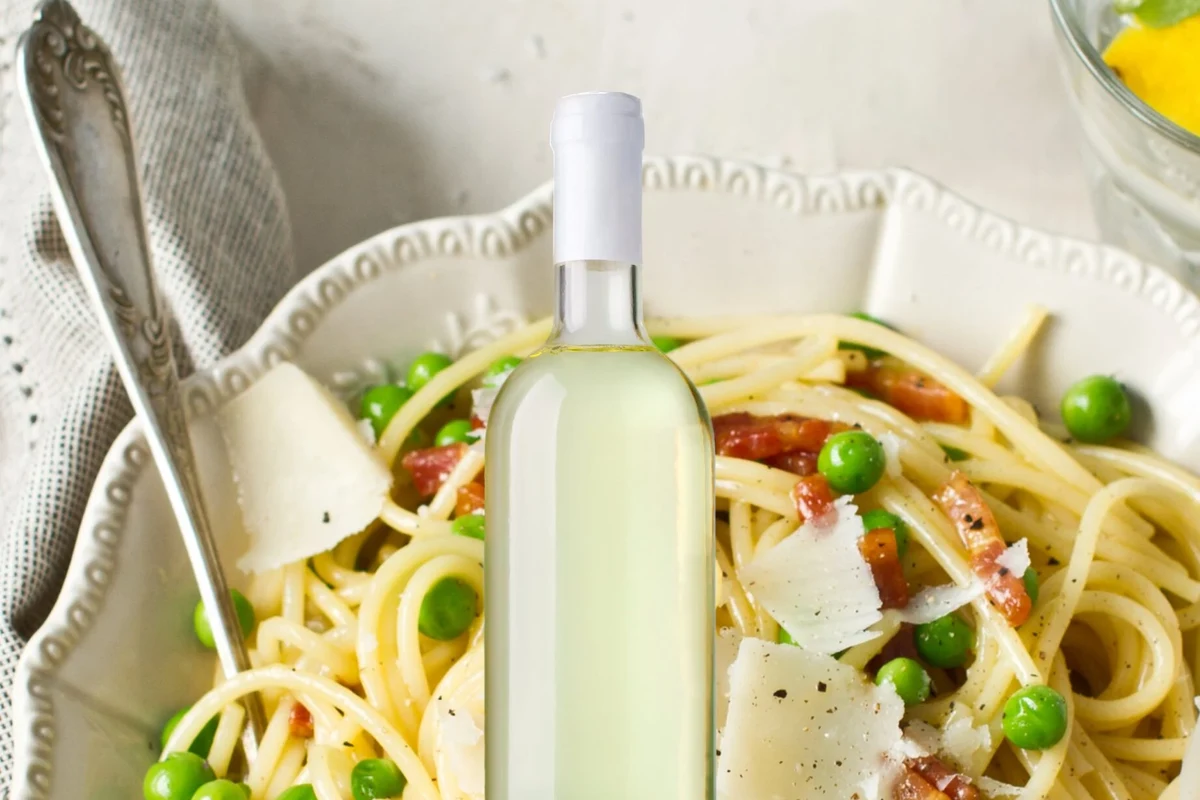 Wine glasses beside pasta dishes with marinara, Alfredo, pesto, and lasagna on a dinner table