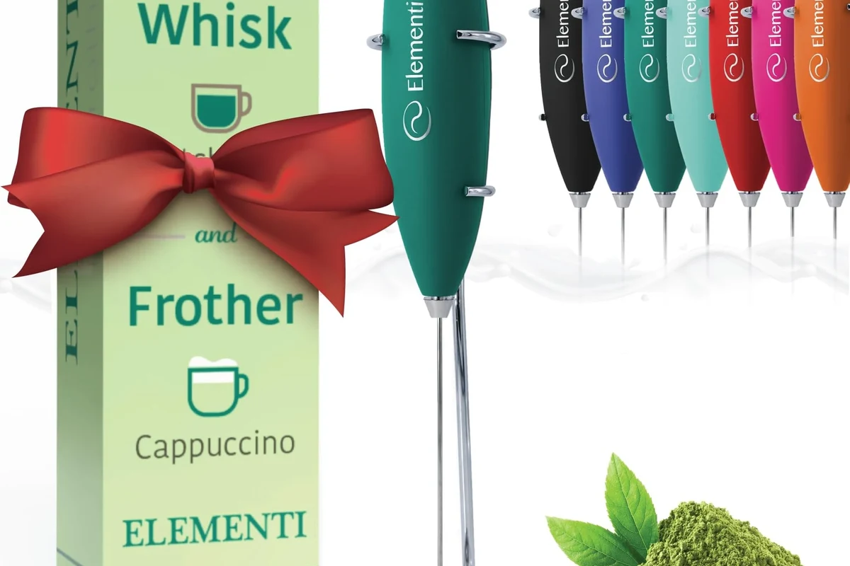 Electric milk frother mixing matcha powder in a small cup on a kitchen counter